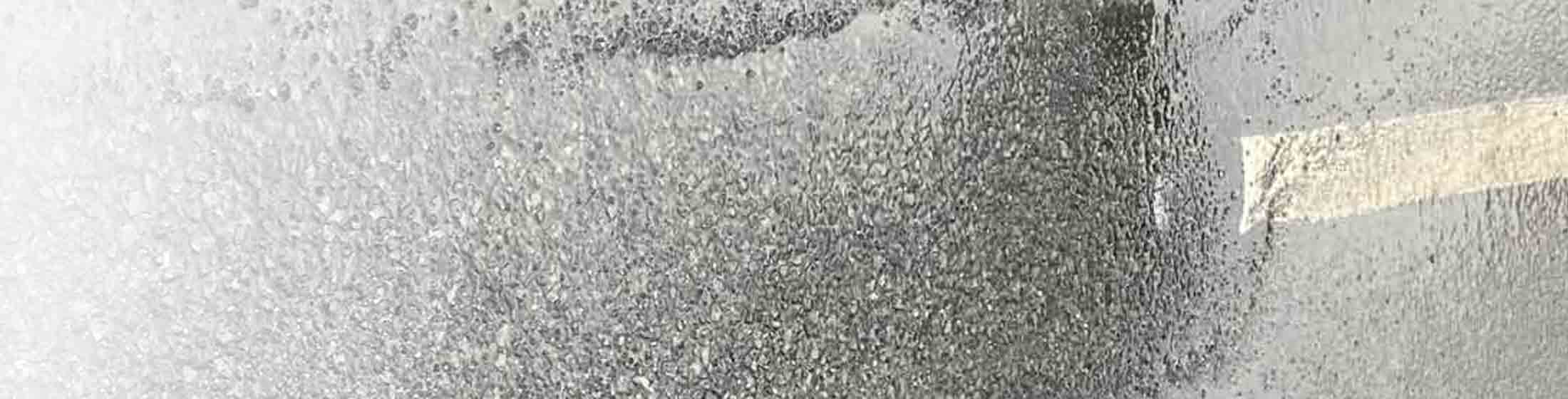 A road surface showing where road marking removal equipment has removed a white line using high pressure water.